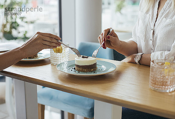 Anonyme junge Frauen teilen einen Kuchen im Café
