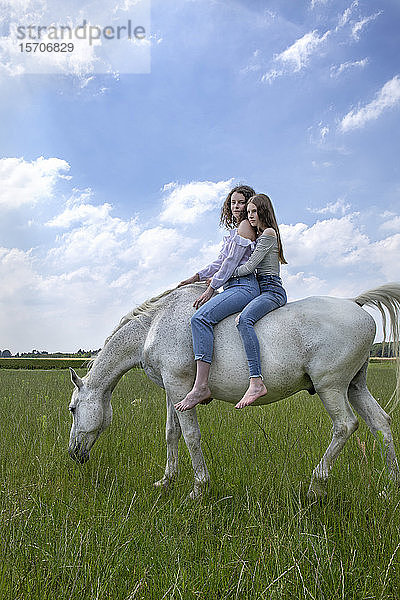 Zwei beste Freunde reiten zusammen auf einem Pferd