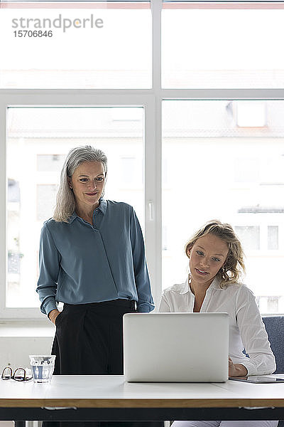 Zwei Geschäftsfrauen benutzen gemeinsam einen Laptop am Schreibtisch im Büro