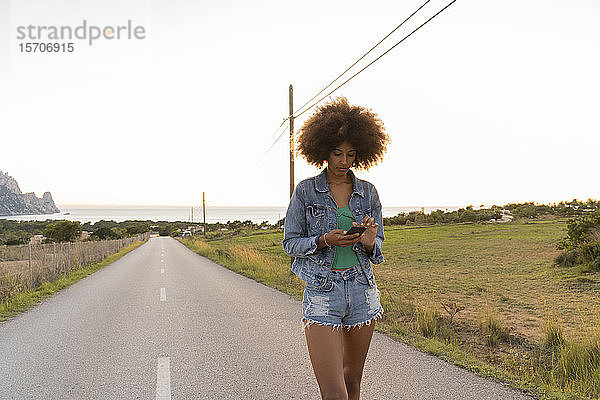 Junge Frau unterwegs mit Smartphone  Ibiza