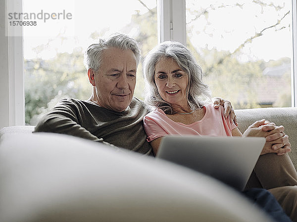 Älteres Ehepaar mit Laptop entspannt zu Hause auf der Couch