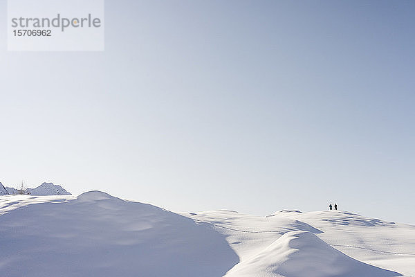 Berglandschaft mit Neuschnee  zwei Wanderer am Aussichtspunkt  Valmalenco  Italien