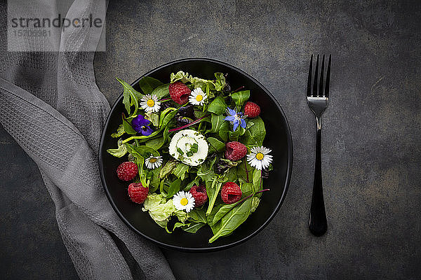 Schüssel frischer Salat mit Rucola  Spinat  Mangold  Eichenblatt  Lollo Rosso Salat  Maissalat  Himbeeren  Frischkäse  Schnittlauch und essbaren Blumen