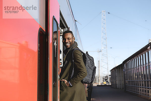 Porträt eines glücklichen Mannes beim Einsteigen in einen Zug