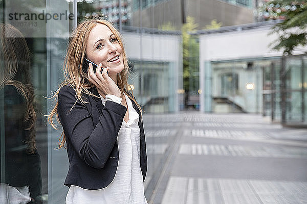 Lächelnde Geschäftsfrau am Telefon in der Stadt