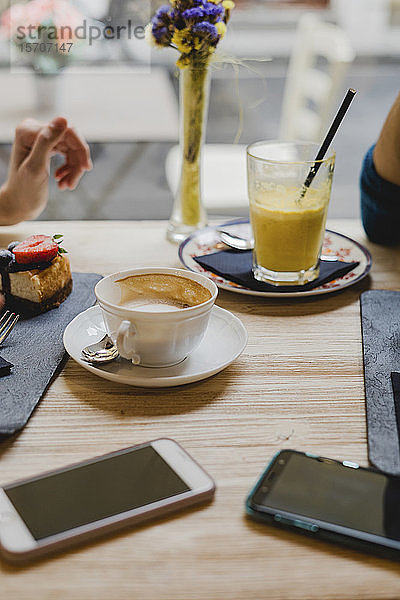 Mobiltelefone  Kuchen und Getränke auf dem Tisch in einem Café