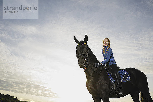 Porträt einer lächelnden Frau auf dem Pferd auf dem Land