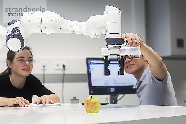 Studenten  die an einem Universitätsinstitut Robotik studieren und mit einem Apfel experimentieren