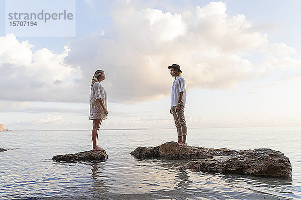 Auf Felsen vor dem Meer stehendes junges Paar  Ibiza  Balearen  Spanien