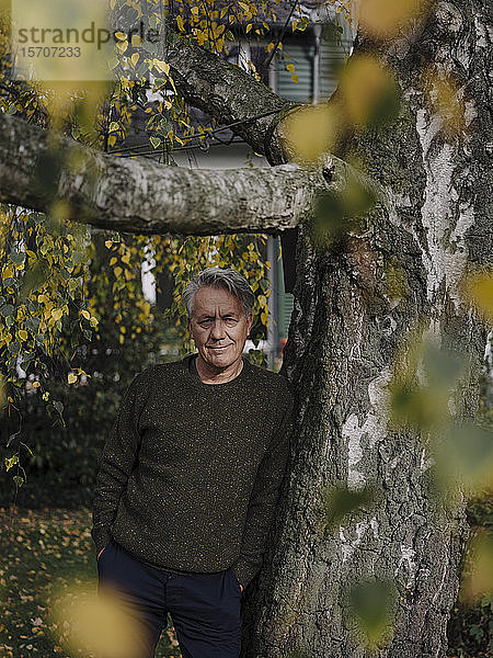 Porträt eines älteren Mannes am Baum im Garten