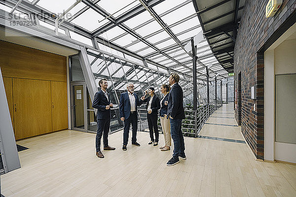 Zuversichtliche Geschäftsleute sprechen in modernem Bürogebäude