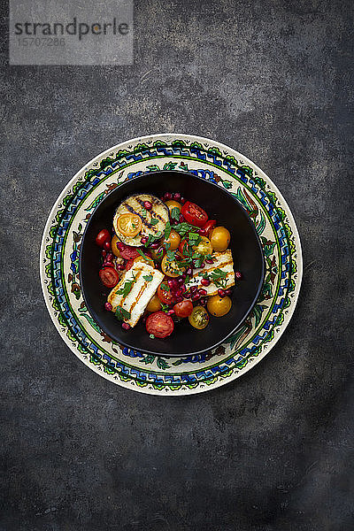 Persischer Salatteller mit Tomaten  gegrilltem Halloumi-Käse  Auberginen  Granatapfelkernen  Sumach  schwarzem Sesam und Petersilie