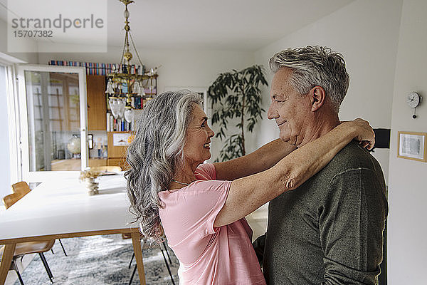 Glückliches älteres Paar umarmt sich zu Hause im Wohnzimmer