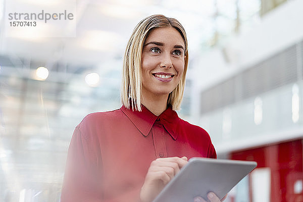 Lächelnde junge Geschäftsfrau im roten Hemd mit Tablette