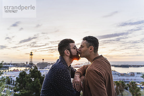 Schwules Paar küsst sich auf einem Aussichtspunkt über der Stadt mit Blick auf den Hafen  Barcelona  Spanien