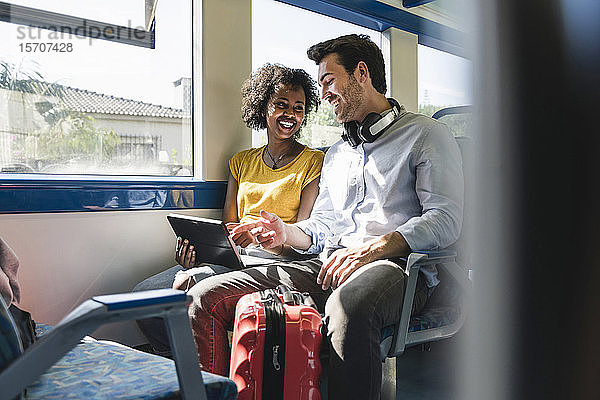 Glückliches junges Paar mit Tablette in einem Zug