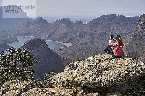Frau fotografiert mit ihrem Mobiltelefon vor einem wunderschönen Landschaftshintergrund  Blyde River Canyon  Südafrika
