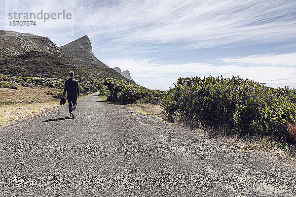 Rückansicht eines Geschäftsmannes  der barfuss auf einer Landstrasse geht  Cape Point  Western Cape  Südafrika