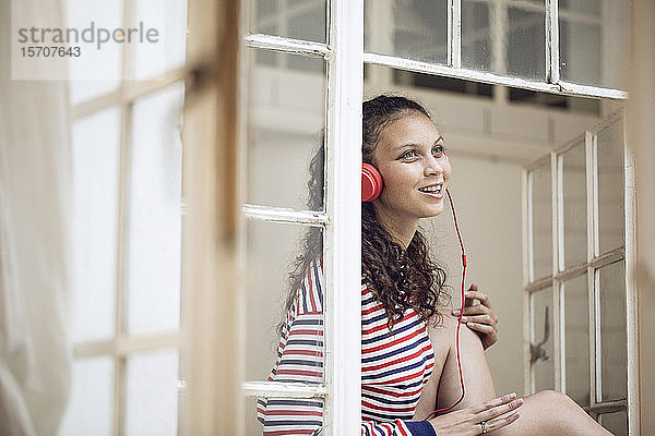 Glückliche junge Frau am Fenster  die Musik hört