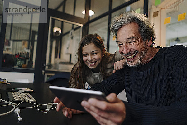 Glücklicher Gelegenheits-Senior-Businessmann und Mädchen benutzen Tablet im Büro