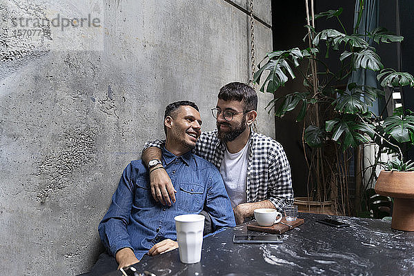 Schwules Paar entspannt sich gemeinsam in einem Café im Freien  Barcelona  Spanien