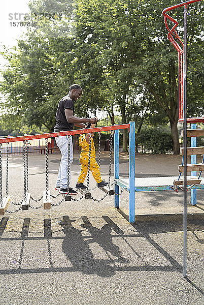 Vater und Tochter balancieren auf Holzstufen auf einem Spielplatz