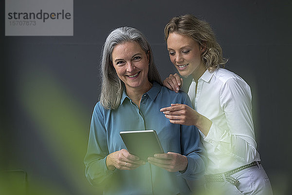 Zwei lächelnde Geschäftsfrauen teilen sich eine Tablette