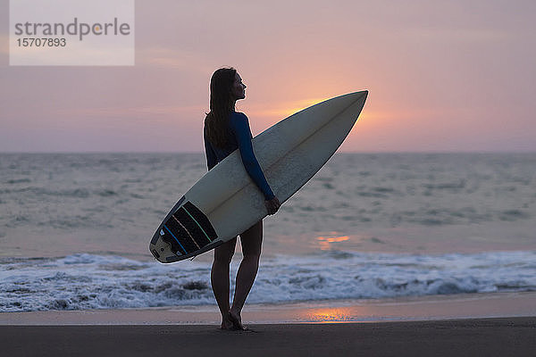 Junge Frau mit Surfbrett am Strand  Strand von Kedungu  Bali  Indonesien