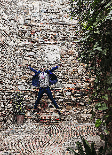 Aufgeregter eleganter Mann springt auf ein altes Gebäude