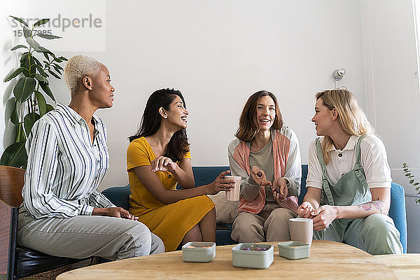Vier Frauen sitzen auf der Couch und unterhalten sich