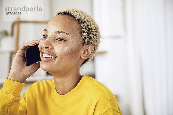 Porträt einer glücklichen jungen Frau am Telefon zu Hause