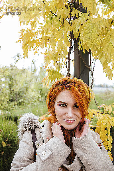 Porträt einer lächelnden jungen Frau mit orange gefärbtem Haar im Herbst