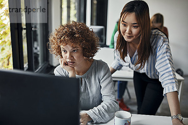 Zwei Geschäftsfrauen schauen auf den Desktop-PC im Büro