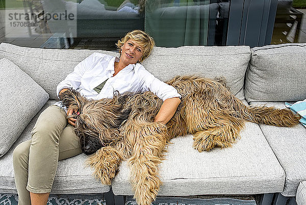 Frau entspannt sich zu Hause mit Hund auf der Terrasse
