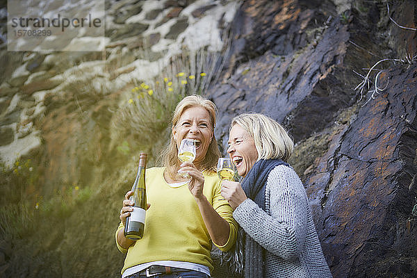 Zwei lachende reife Frauen trinken Wein im Freien