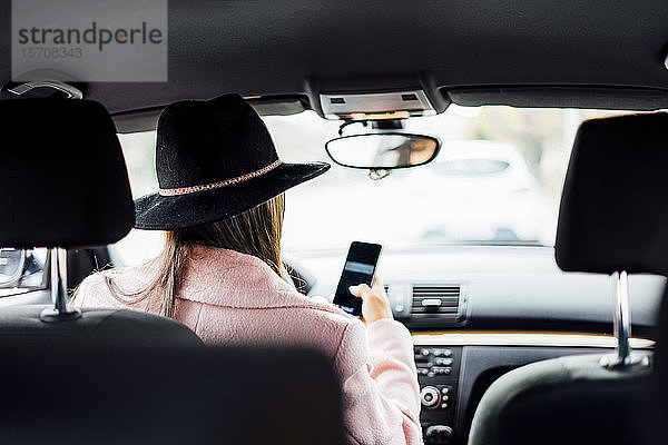 Geschäftsfrau benutzt Smartphone während der Fahrt