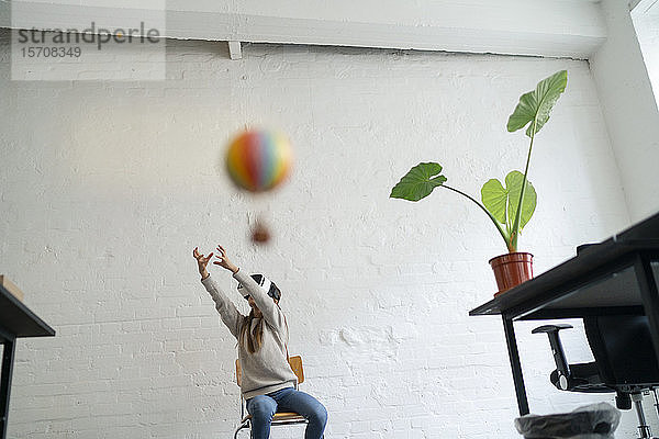 Mädchen mit VR-Brille versucht  im Büro einen Heißluftballon zu fangen