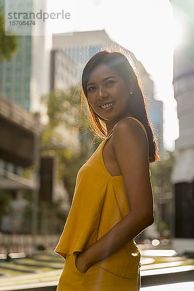 Porträt einer modischen  gelb gekleideten Frau im Gegenlicht stehend