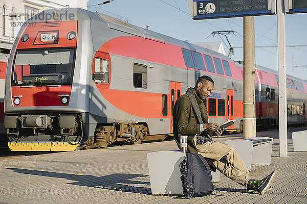 Stilvoller Mann liest Dokumente beim Warten auf den Zug