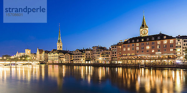 Schweiz  Kanton Zürich  Zürich  Fluss Limmat und Altstadtgebäude entlang der beleuchteten Straße Limmatquai in der Abenddämmerung