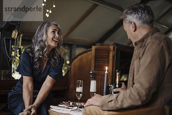 Glückliches älteres Ehepaar bei einem Candlelight-Dinner auf einem Boot im Bootshaus