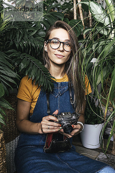 Porträt einer jungen Frau mit einer Kamera in einem kleinen Gartenbaubetrieb