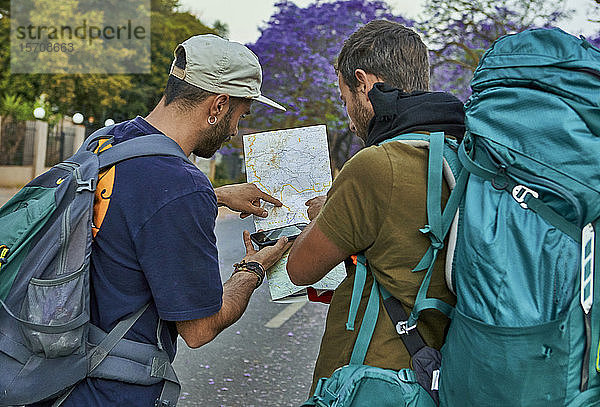 Zwei Rucksacktouristen überprüfen eine Karte auf einer Straße