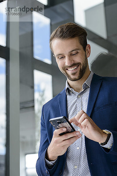 Lächelnder junger Geschäftsmann mit Smartphone