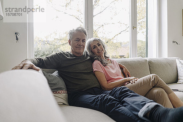 Porträt eines älteren Paares  das sich zu Hause auf der Couch entspannt