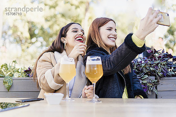 Zwei Freundinnen bei einem Selfie im Freien in einem Café