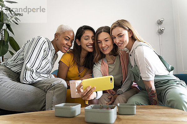 Vier Frauen sitzen auf der Couch und machen ein Selfie