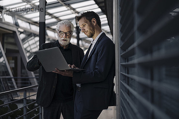 Zwei Geschäftsleute benutzen gemeinsam einen Laptop im Büro