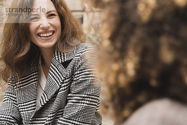 Zwei glückliche Frauen  die sich draußen in der Stadt treffen und unterhalten