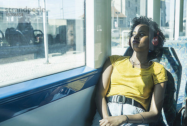 Junge Frau mit Kopfhörern entspannt sich in einem Zug